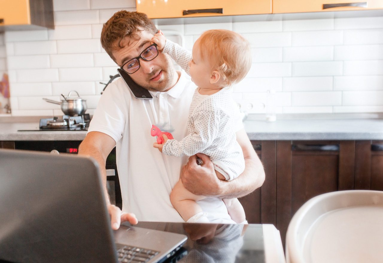 man in keuken met baby probeert te werken